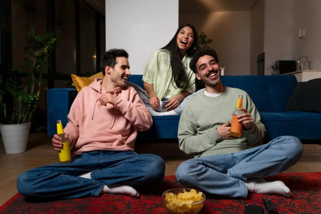 Tres amigos riendo en el salón mientras ven la televisión durante una prueba IPTV gratis